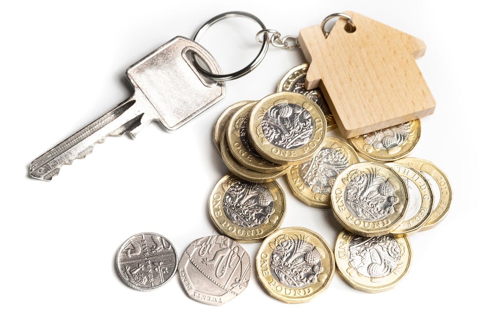 key to a property on top of a pile of pound coins