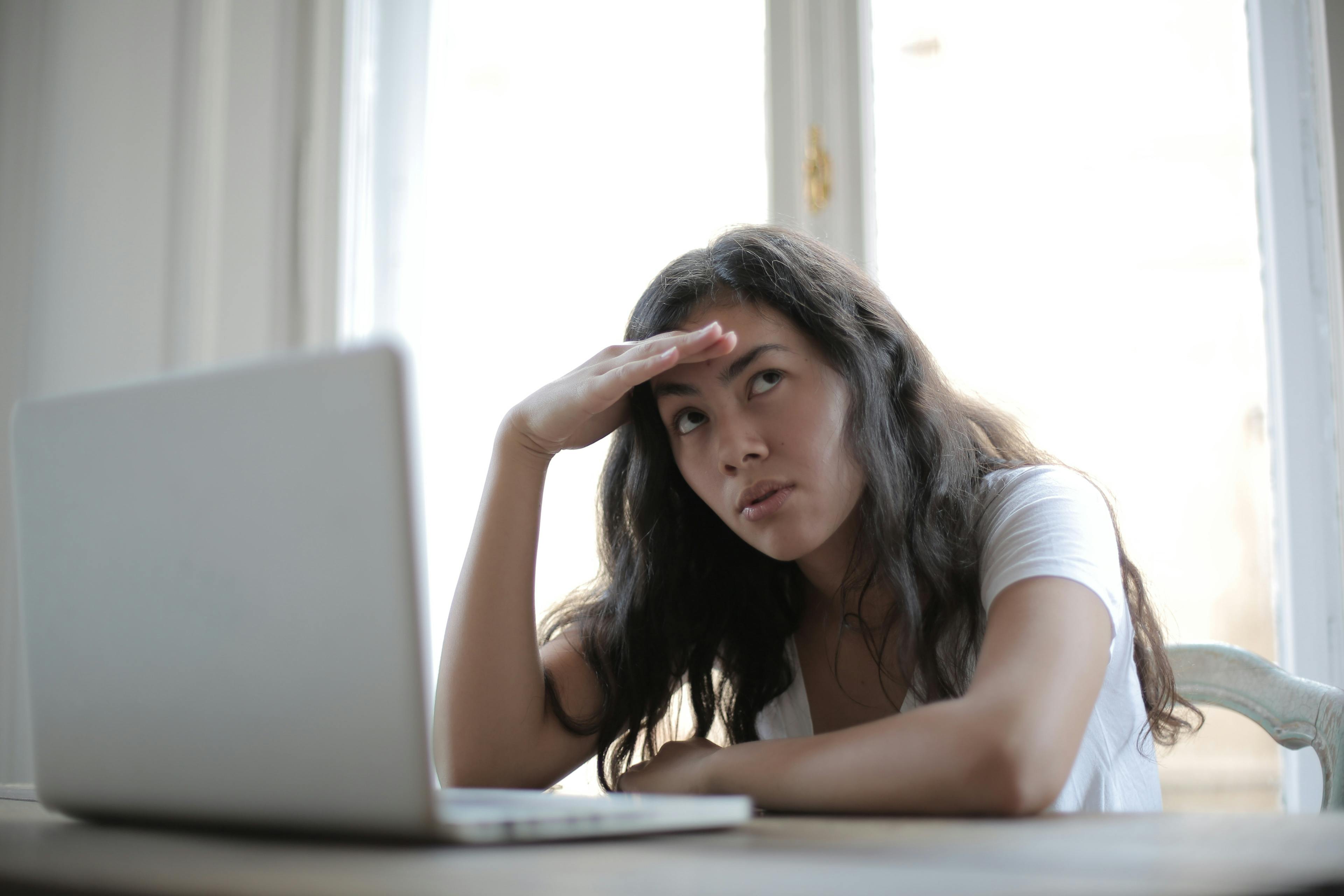 Young woman looking stressed at her laptop screen.