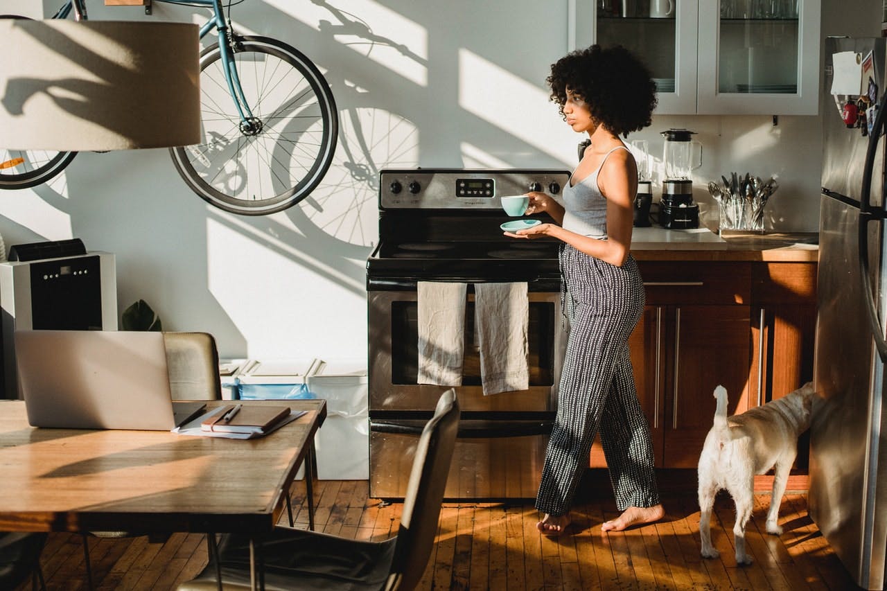 Woman in modern kitchen thinks about her interest only mortgage whilst drinking coffee