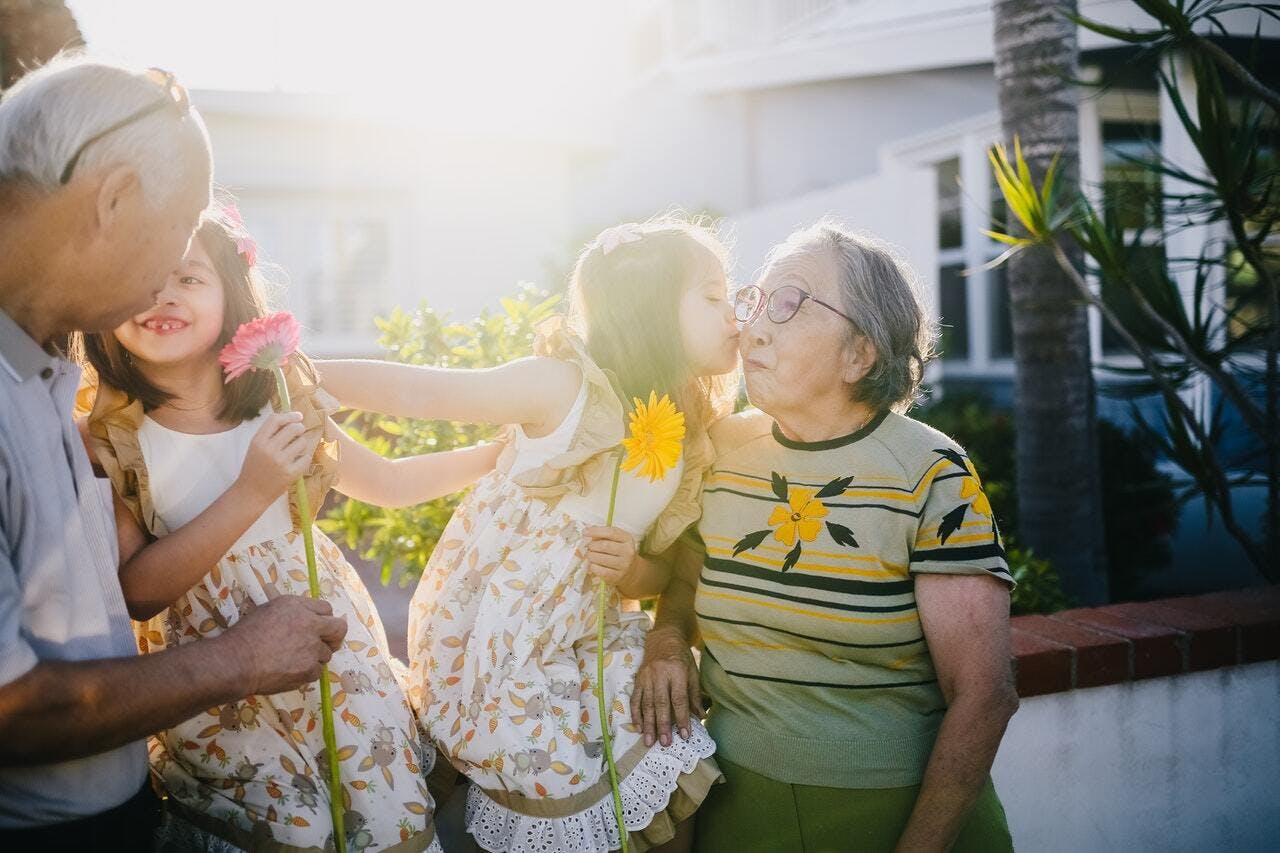 Old grandmother holding flowers with her grandchildren