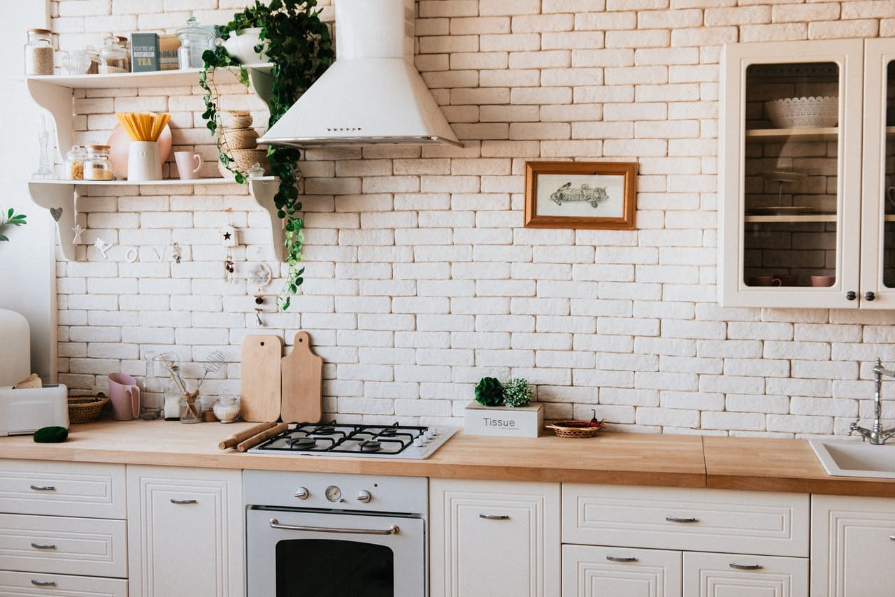 tidy neutral tone kitchen with hanging plant, and white painted brick wall