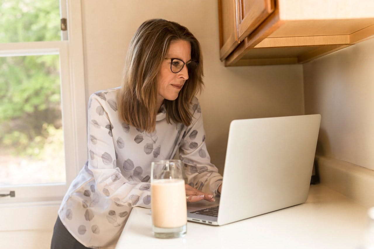 Woman researches on laptop in kitchen