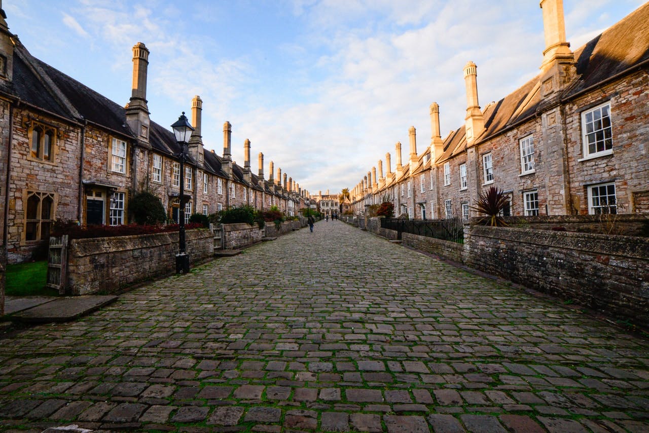 View up a cobbled street, lined with terraced stone cottages, with old chimneys