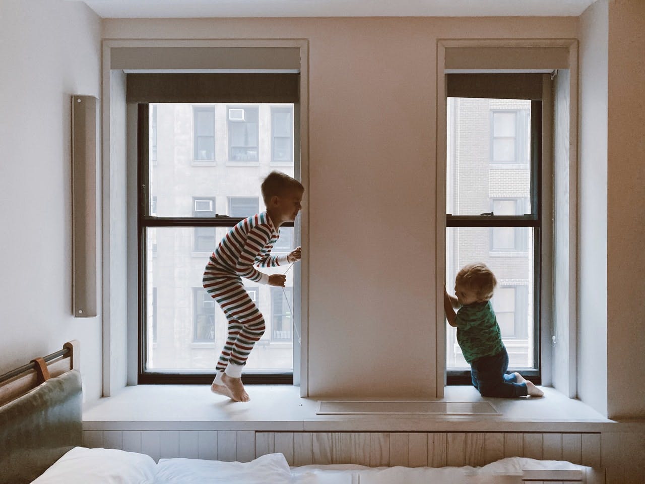two young children playing in window of empty bedroom
