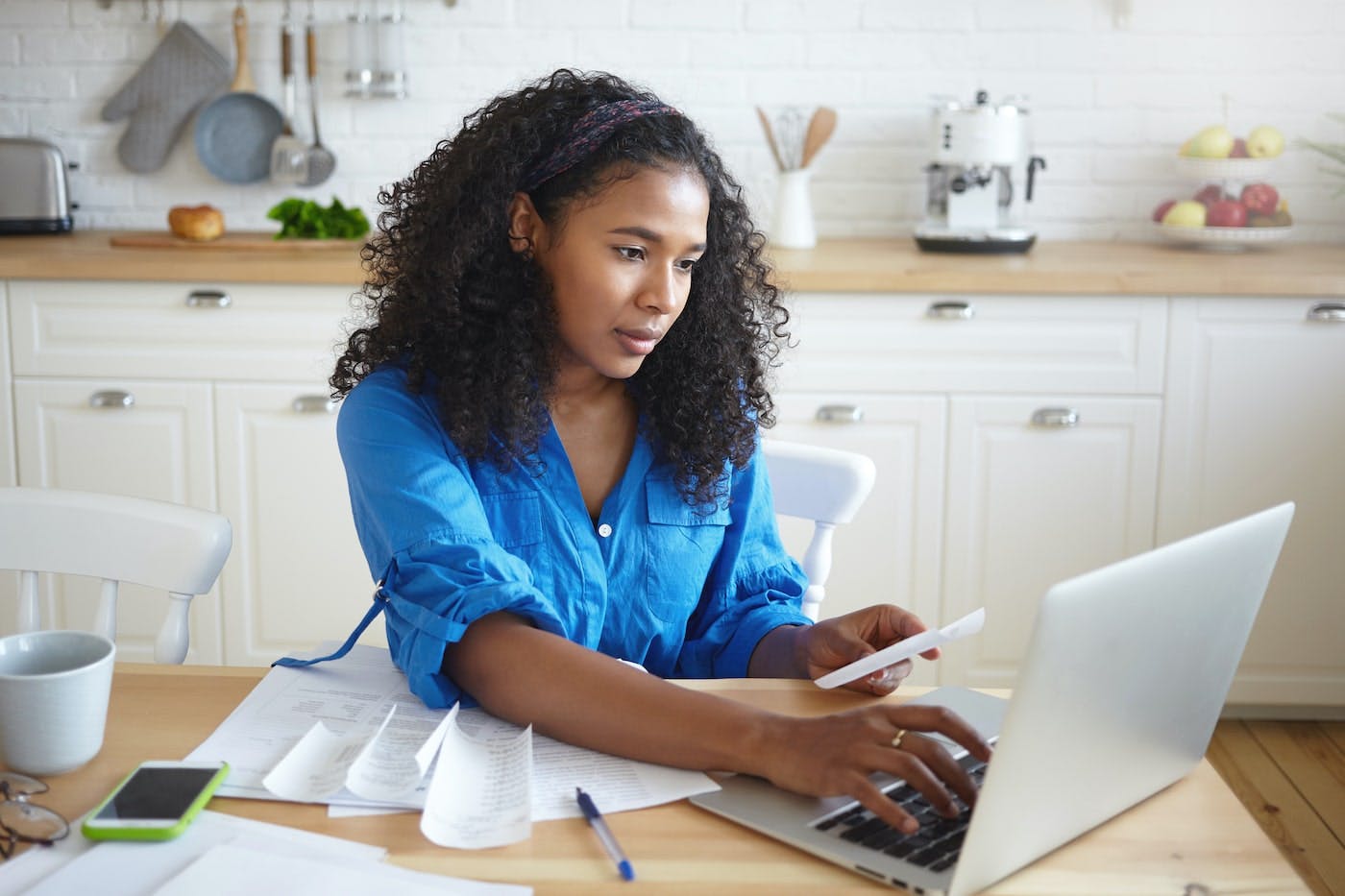 Woman sitting in a kitchen looking at a laptop.