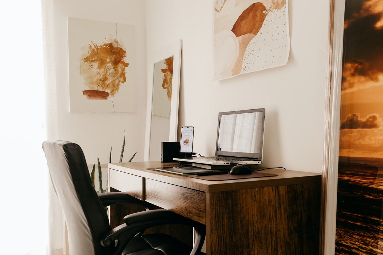 a modern home office with leather chair, wooden table, and laptop 