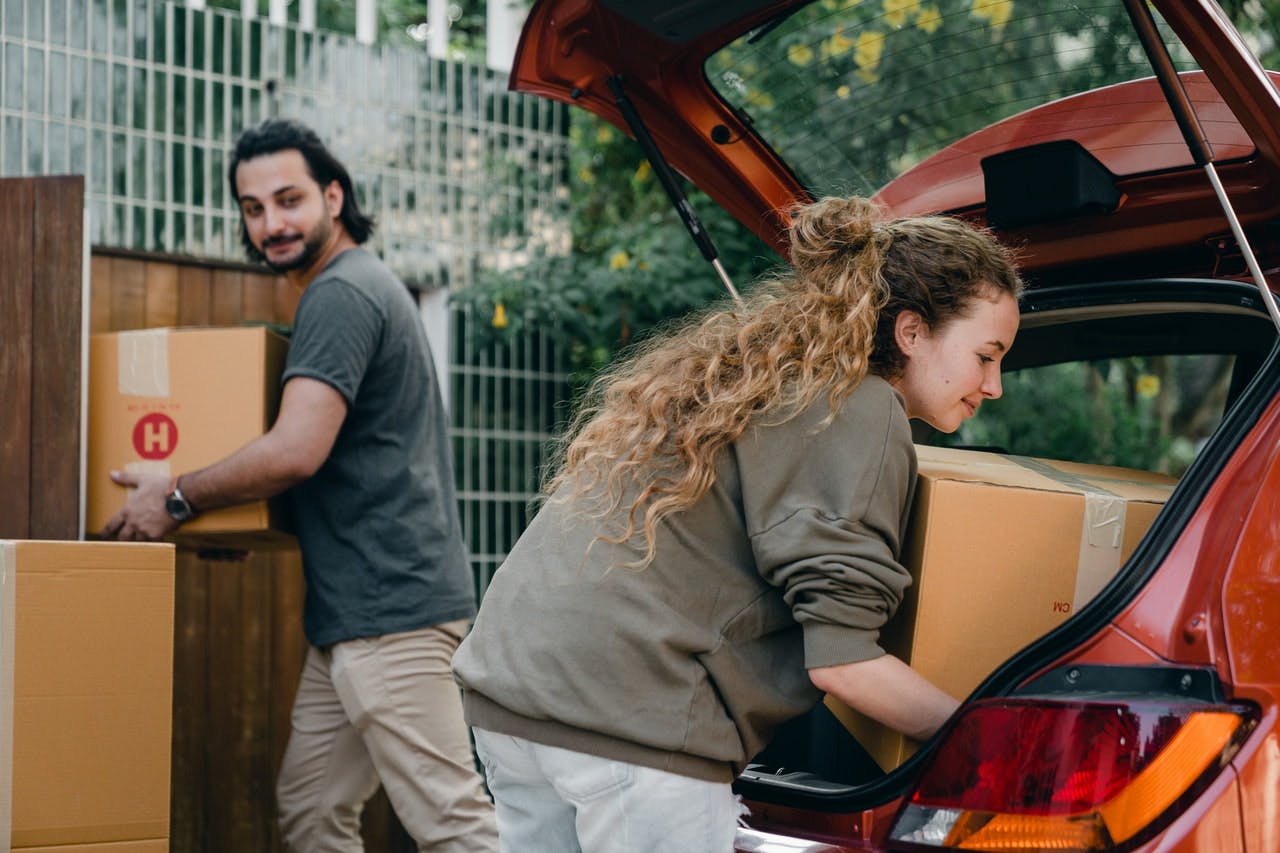 Couple moving boxes out of a car.