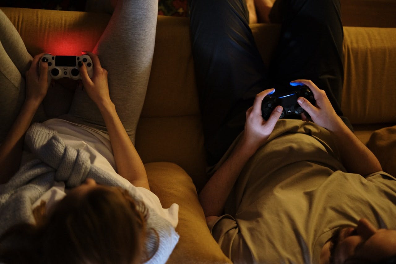 couple sat on sofa playing on video game console