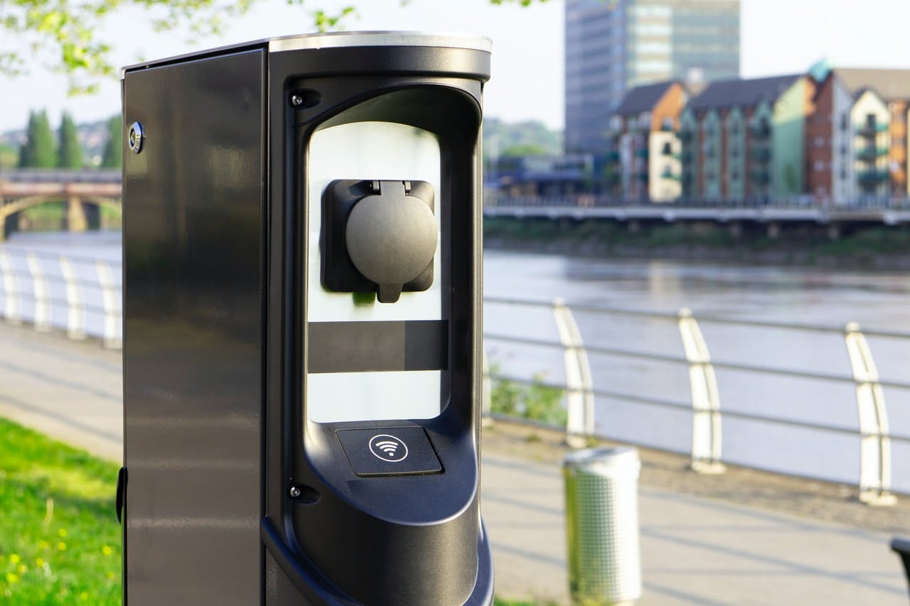 Public electric vehicle charger by a river.