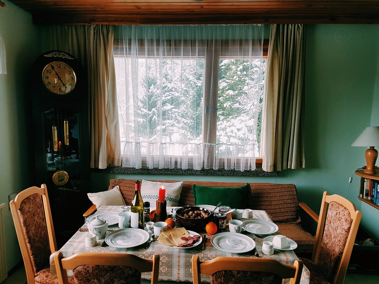 A table set for a meal next to a window with snow covered trees outside