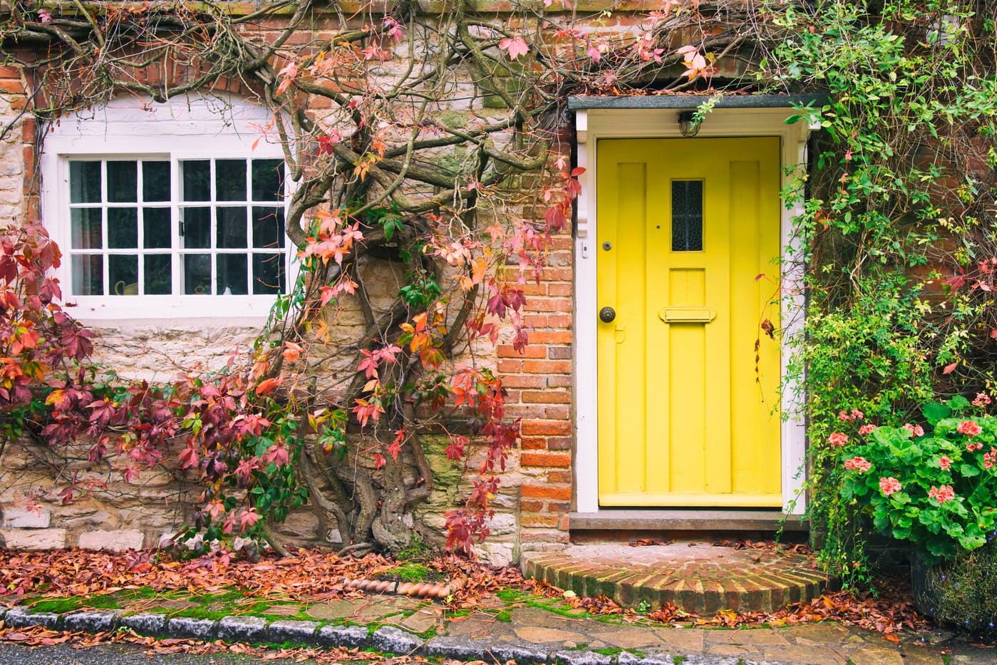An old picturesque house with a yellow door with ivy running down it.