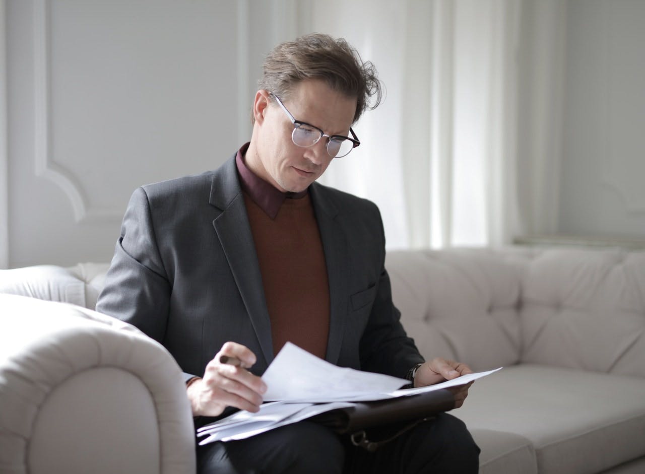Male solicitor sat on white sofa looking through notes