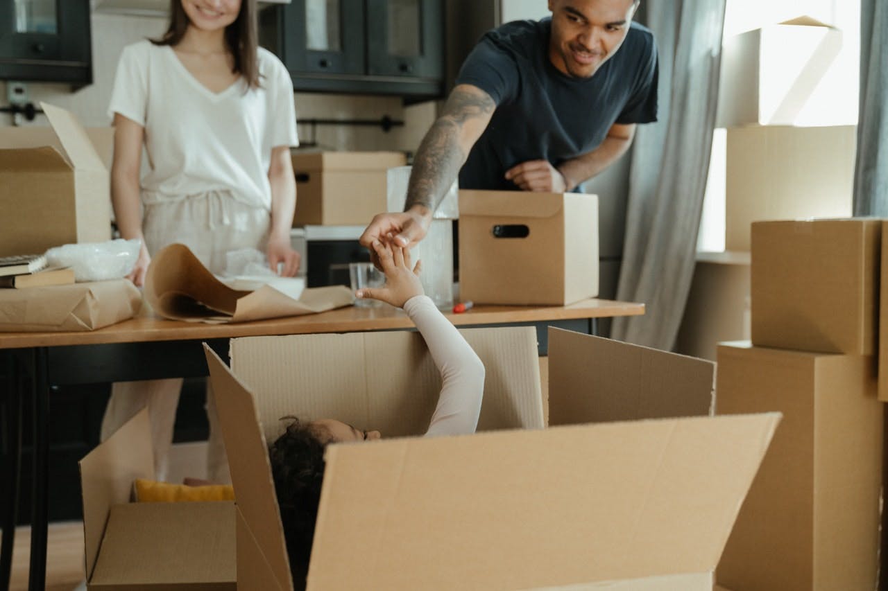 Young couple and child packing moving boxes in their modern kitchen